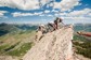 Climbers crawling across very thin and steep rocks along a mountain ridge.